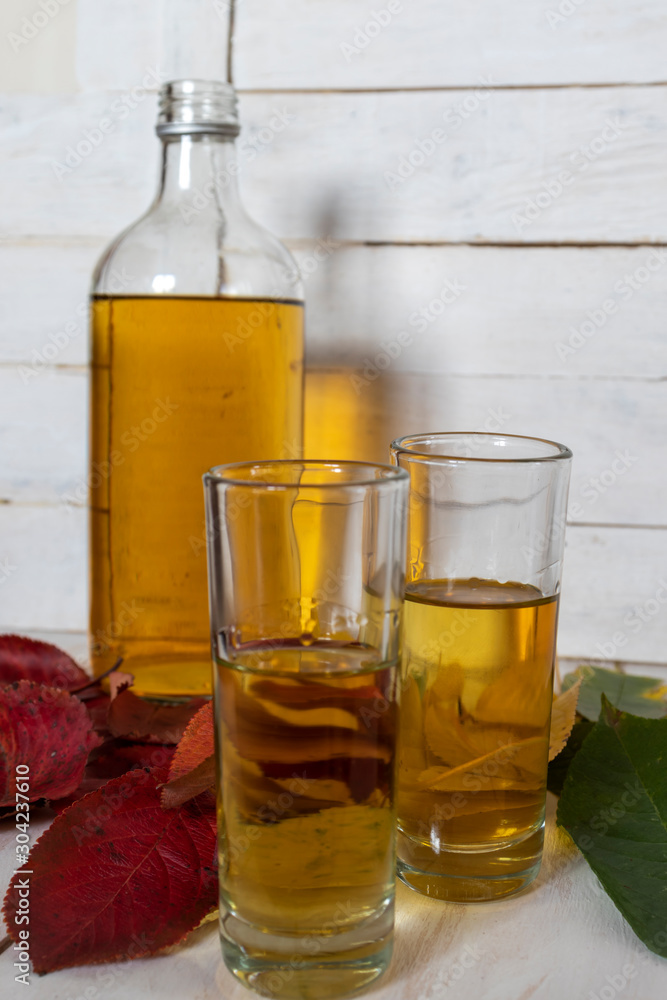 Bottle and glasses of brandy on the background of autumn leaves Bottle and glasses of brandy on the background of autumn leaves