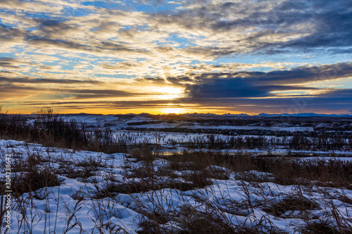 Cold winter sunset over the distant Rocky Mountains with snow in the foreground and winding Bow River below. Calgary  Alberta.
