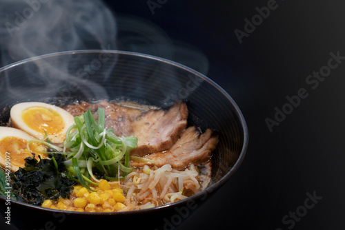 Hot delicious Japanese ramen noodles with pork egg corn scallions and seaweed in black background. Copy Space.