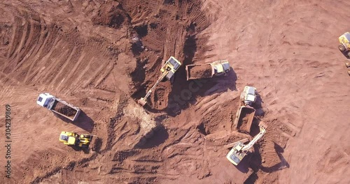 Top down view of several excavators working on a construction site. Heavy industrial machinery. Excavators loading Articulated hauler Trucks.