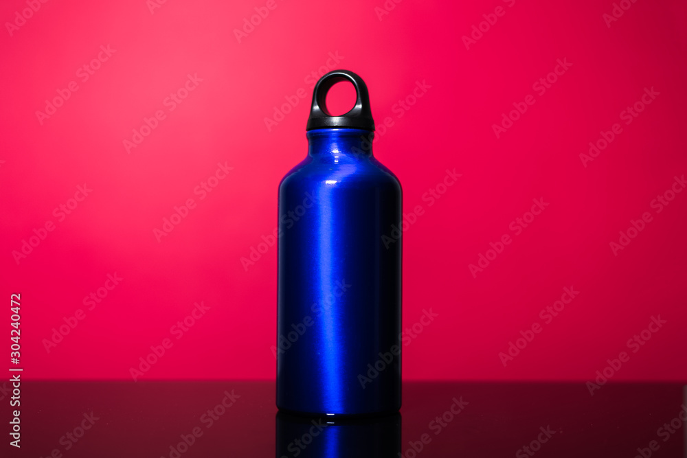 Classic blue of aluminium thermo eco water bottle isolated on pink coral background.