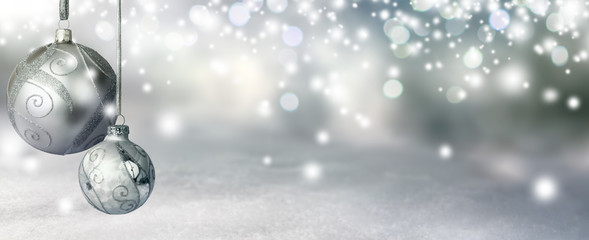 Elegant Christmas background in silver shades, with two baubles hanging and glittering highlights creating a magical atmosphere