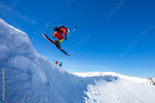 A skier is riding and jumping at mountain terrain.