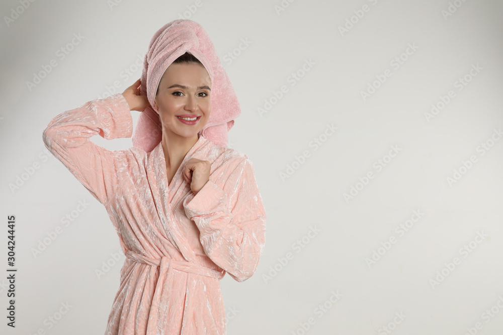 Beautiful young woman in bathrobe on light background. Space for text Beautiful young woman in bathrobe on light background. Space for text