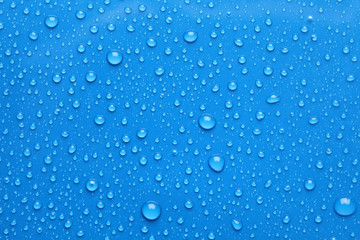 Water drops on blue background, top view