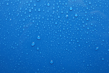 Water drops on blue background, top view