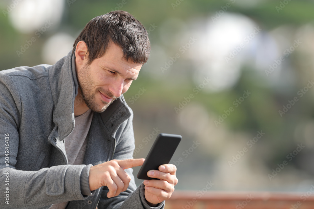 Serious man checking mobile phone app in winter Serious man checking mobile phone app in winter