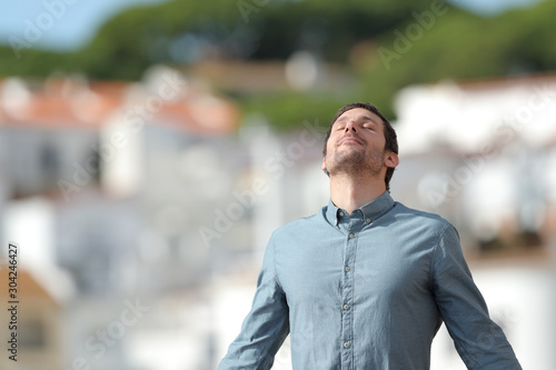 Relaxed man breathing deep fresh air in a rural town