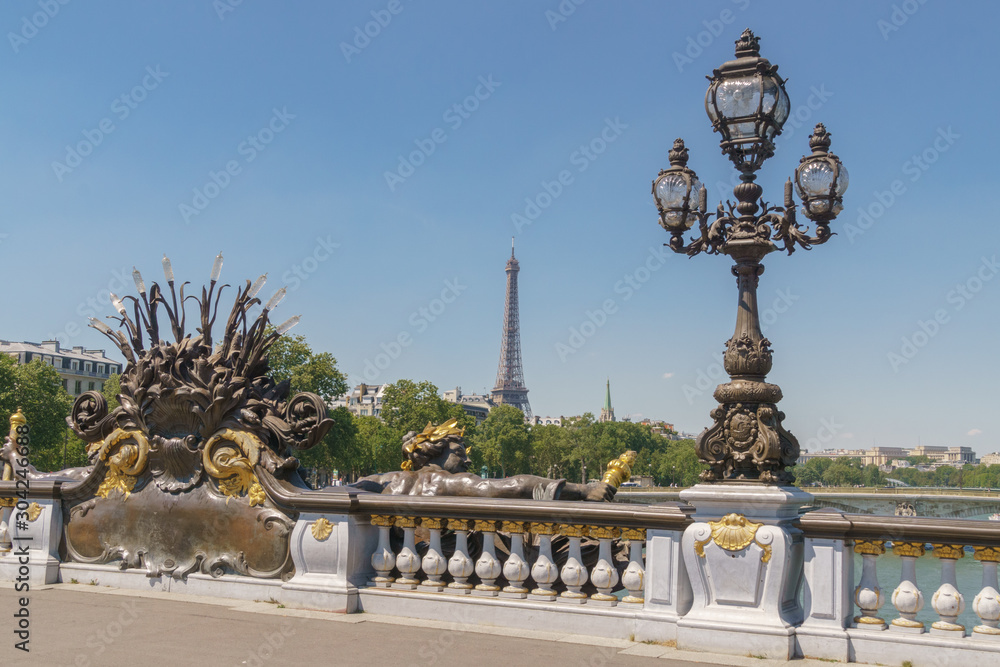 Obraz premium Pont Alexandre III details with the Eiffel Tower in the background, with blue sky