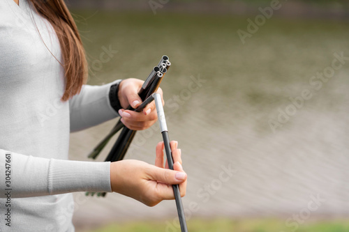 Close-up girl holding rods for camping tent. Camping with a tent. Lake on the background