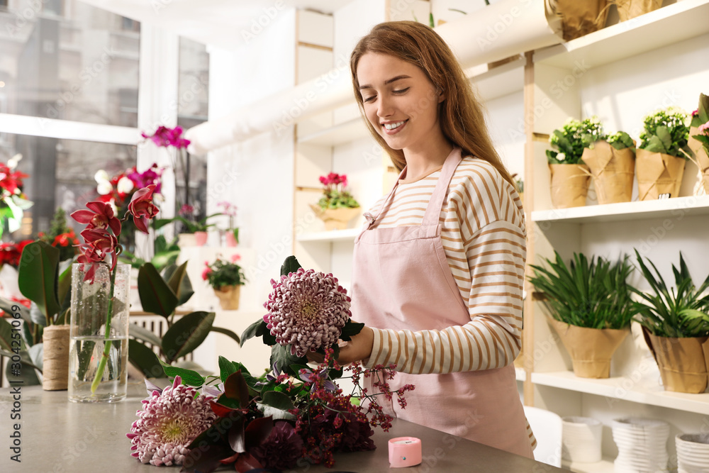 Florist making bouquet with fresh flowers at table in shop