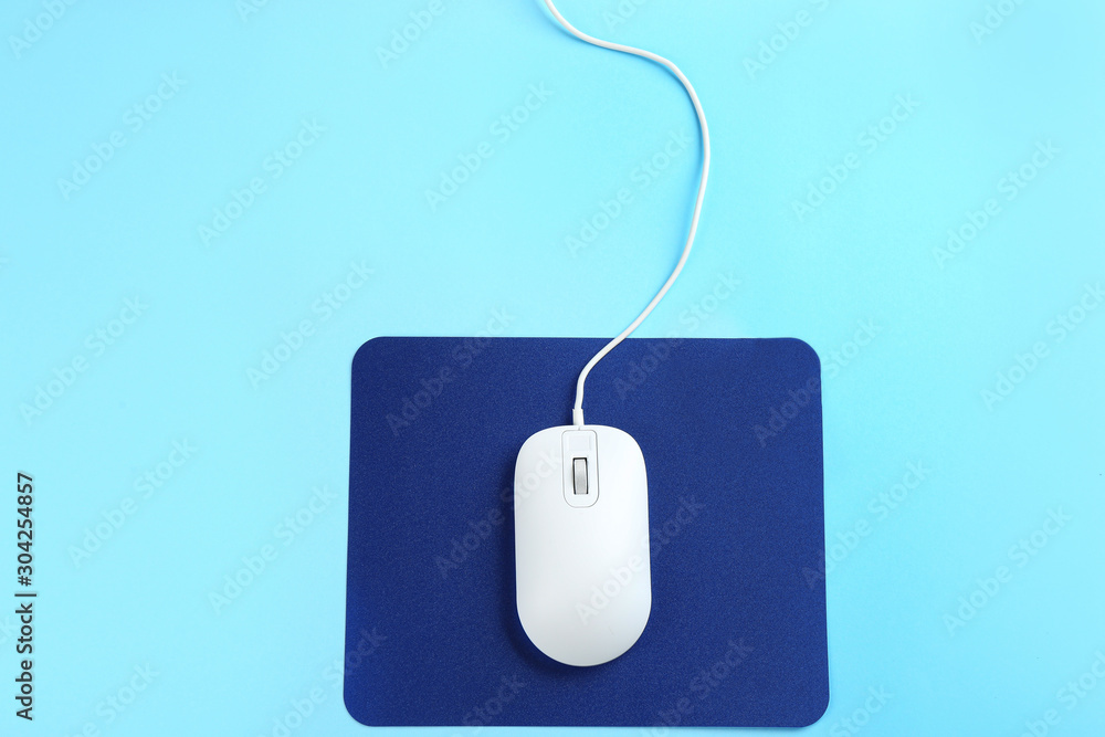 Modern wired mouse and pad on light blue background, top view Modern wired mouse and pad on light blue background, top view