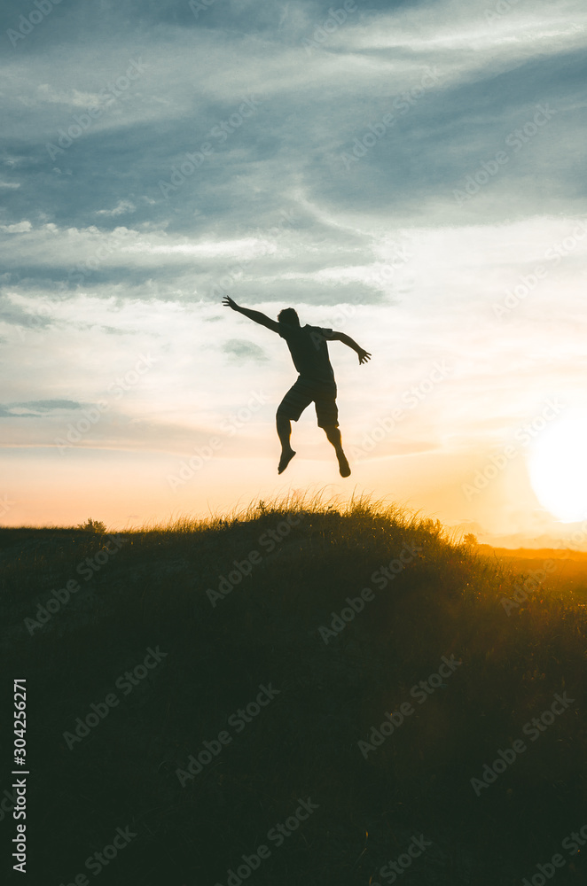 silhouette of young man jumping on sunset background of blue sky silhouette of young man jumping on sunset background of blue sky