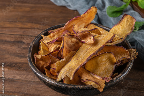 Delicious sweet potato chips in bowl, on table