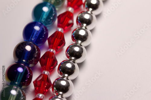 Macro abstract texture border of colorful strands of beads on white background with copy space