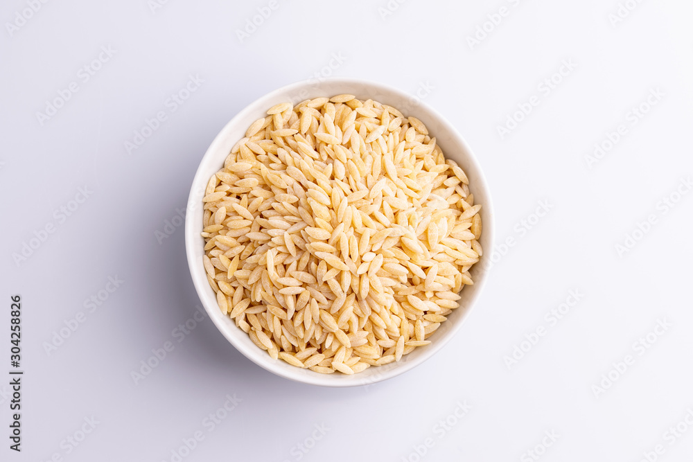 Orzo pasta, isolated on white background. Italian orzo pasta shaped like grains of rice, copy space, soft light Orzo pasta, isolated on white background. Italian orzo pasta shaped like grains of rice, copy space, soft light