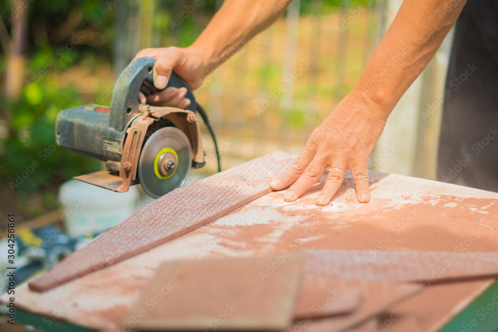 man working at home cutting tile with chainsaw on a makeshift table man working at home cutting tile with chainsaw on a makeshift table