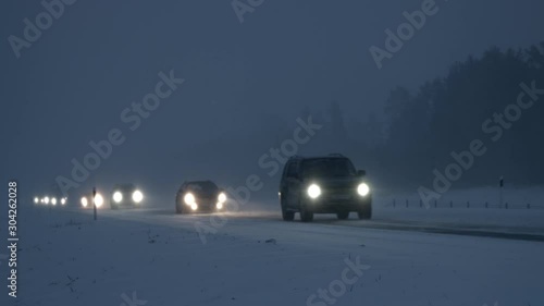 Cars driving on snow covered slippery highway road during blizzard