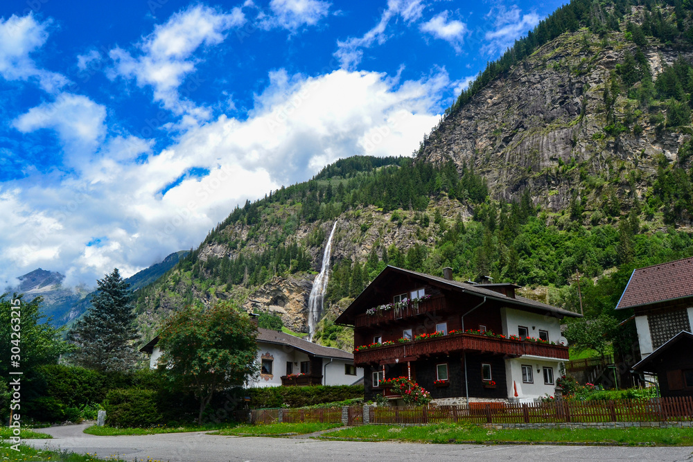 mountain landscape with houses and waterfall with big clouds in the valleys of austria