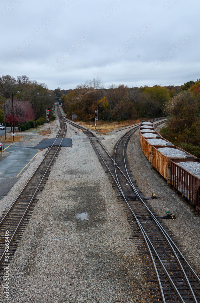 Fototapeta premium Looking down on rail cars loaded with gravel. Multiple train car on the tracks. Sitting in a railroad yard, multiple train tracks are in view. Lot of track switches.