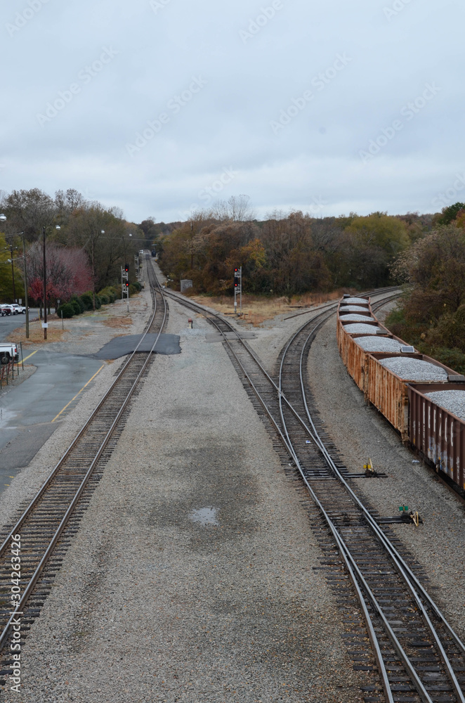 Fototapeta premium Looking down on rail cars loaded with gravel. Multiple train car on the tracks. Sitting in a railroad yard, multiple train tracks are in view. Lot of track switches.