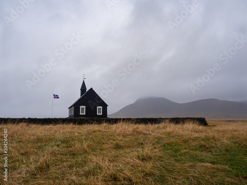 The beautiful and minimalist Búdir church, viewed from behind. With the the natural surroundings in the background an in the foreground. The black church. Snæfellsnes peninsula, Iceland.