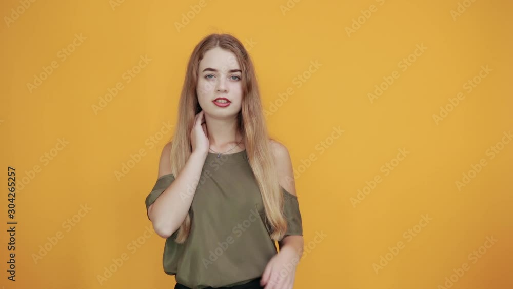 Relaxed young woman in casual clothes keeping eyes closed, with hand behind head isolated on orange wall background in studio. People sincere emotions, lifestyle concept. Relaxed young woman in casual clothes keeping eyes closed, with hand behind head isolated on orange wall background in studio. People sincere emotions, lifestyle concept.