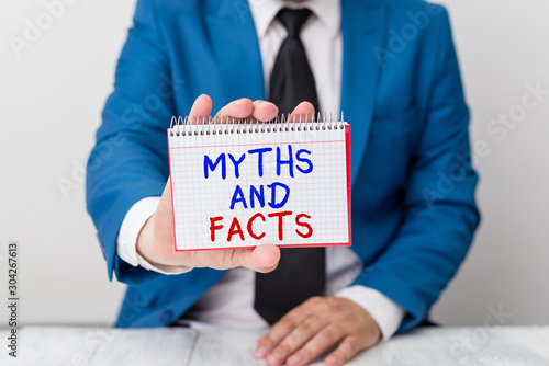 Conceptual hand writing showing Myths And Facts. Concept meaning Oppositive concept about modern and ancient period Man holds empty paper with copy space in front of him Space photo