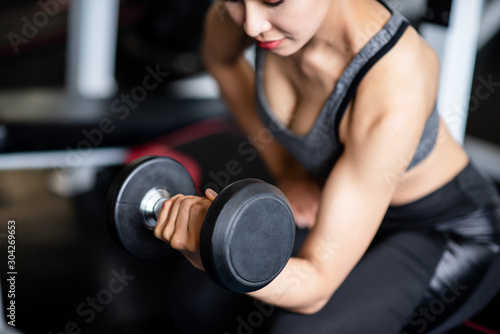 Young healthy woman lifting dumbbells in the gym © Seksan