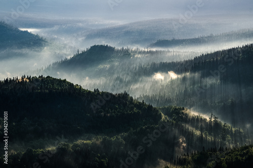 Fotografie Sunrays enlightening the morning mist under a golden light on the valley of the