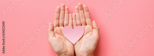 Valentine's day background. Female hands holding pink hearth. Flat lay, top view, mockup, template, copy space. Minimal abstract composition for 14 February celebration