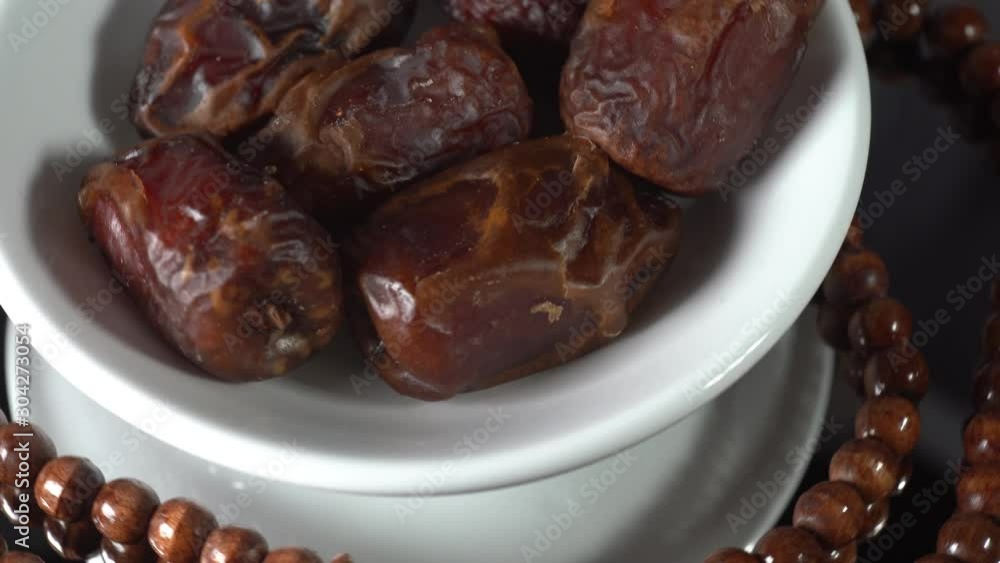 Islamic Concept: Cinematic shot of Tamar (dates) and Tasbih (rosary beads) on a rotating display. Dates usually are eaten during suhoor and iftar in Ramadhan Islamic Concept: Cinematic shot of Tamar (dates) and Tasbih (rosary beads) on a rotating display. Dates usually are eaten during suhoor and iftar in Ramadhan