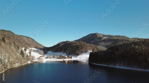 Aerial view, Flight over Walchensee Lake towards a farm in snowy Pine Tree Forest, Upper Bavaria, Germany photo