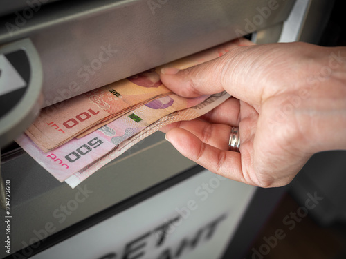 Hand receiving cash money from ATM machine.