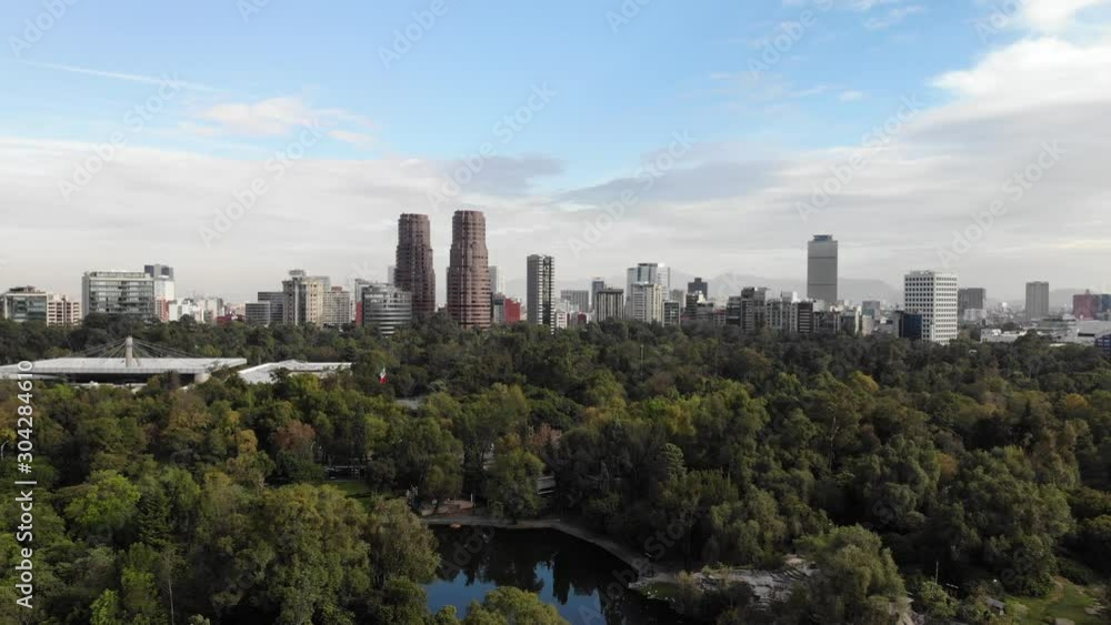 Aerial over Chapultepec Lake with views of the Polanco Skyline at sunrise. Drone flying forward with a blue and cloudy sky Aerial over Chapultepec Lake with views of the Polanco Skyline at sunrise. Drone flying forward with a blue and cloudy sky