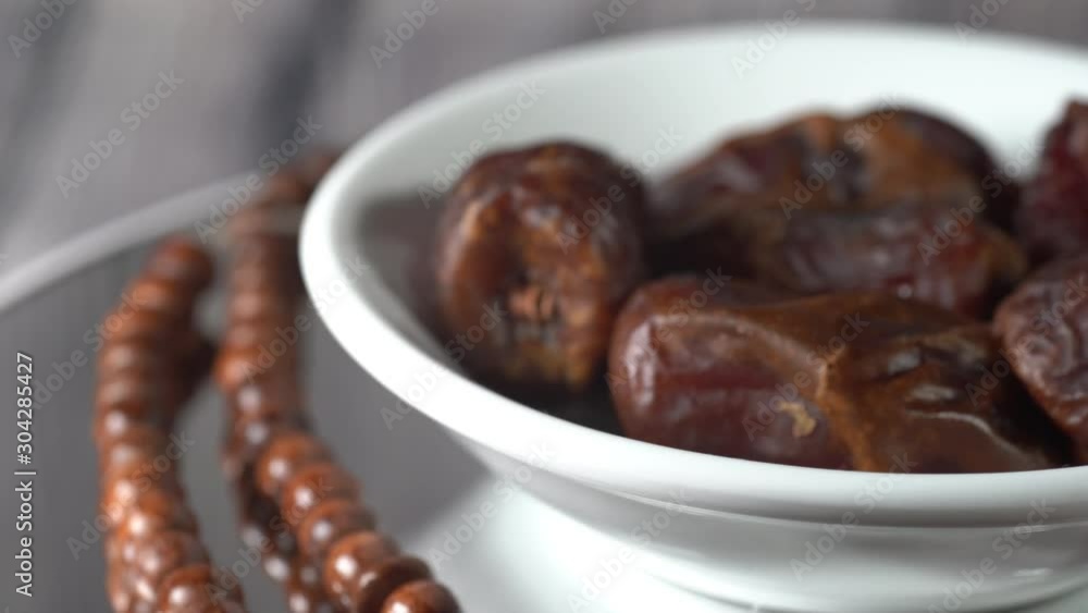 Islamic Concept: Cinematic shot of Tamar (dates) and Tasbih (rosary beads) on a rotating display. Dates usually are eaten during suhoor and iftar in Ramadhan Islamic Concept: Cinematic shot of Tamar (dates) and Tasbih (rosary beads) on a rotating display. Dates usually are eaten during suhoor and iftar in Ramadhan