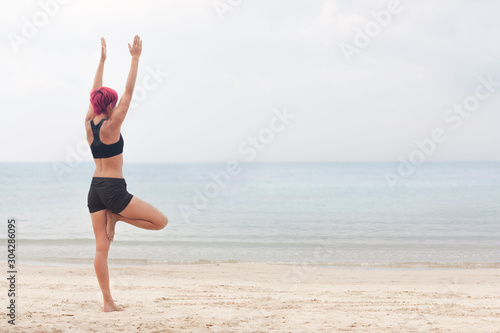 Girl doing yoga on the beach in the early morning