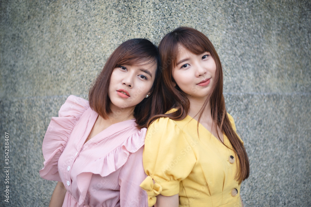 Portrait of two young girl friends posing together with the background of urban city