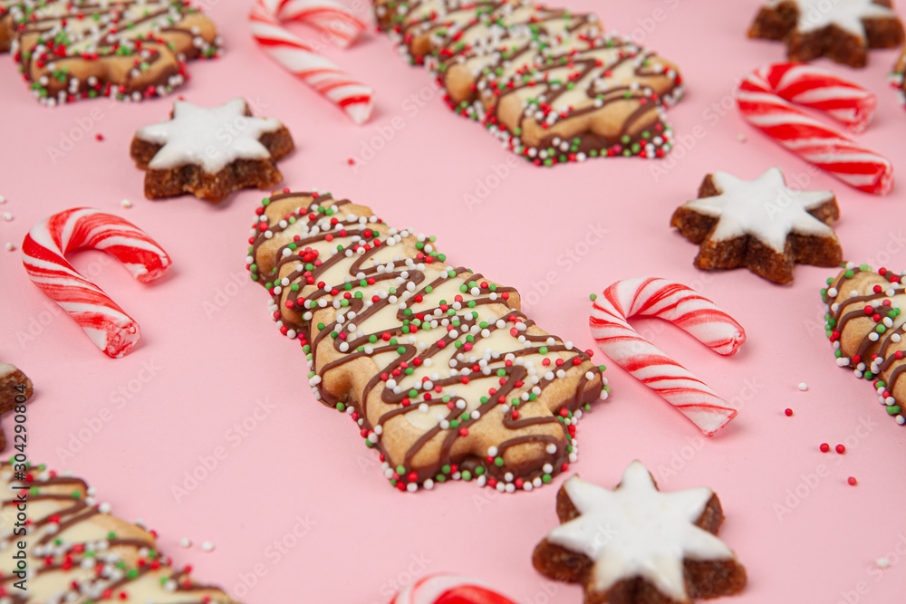 Christmas trees biscuits with candy canes and almond stars - pink background with shallow focus