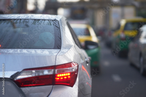 Water frost and dropets on rear wind shield of sedan car on rainy season on traffic background
