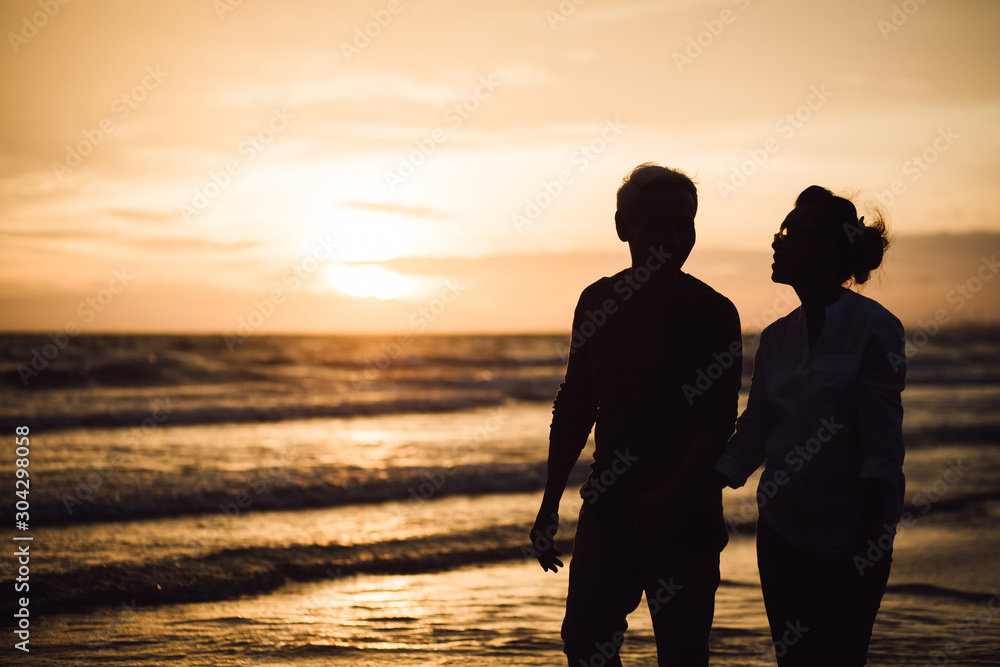 Happy Romantic of retired couple holding hands and walking together each other talking happily. Love is everything. evening light. Retirement age concept and love