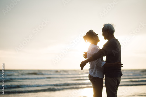 Romantic loving senior caress beloved husband cuddling and looking in eyes. on beach during sunset near sea, Elderly love,image not focus. Retirement age concept and love
