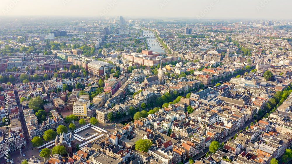 Amsterdam, Netherlands. Flying over the city rooftops towards Amsterdam Central Station ( Amsterdam Centraal ), Aerial View - obrazy, fototapety, plakaty 