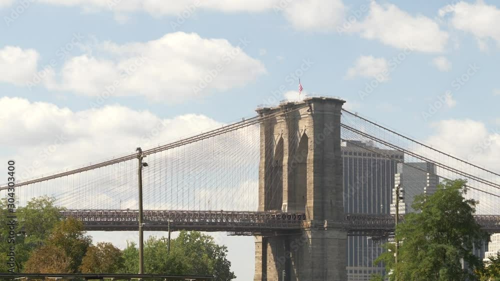 Pan towards Manhattan across the span of NYC's Brooklyn Bridge under clouds in skies Pan towards Manhattan across the span of NYC's Brooklyn Bridge under clouds in skies