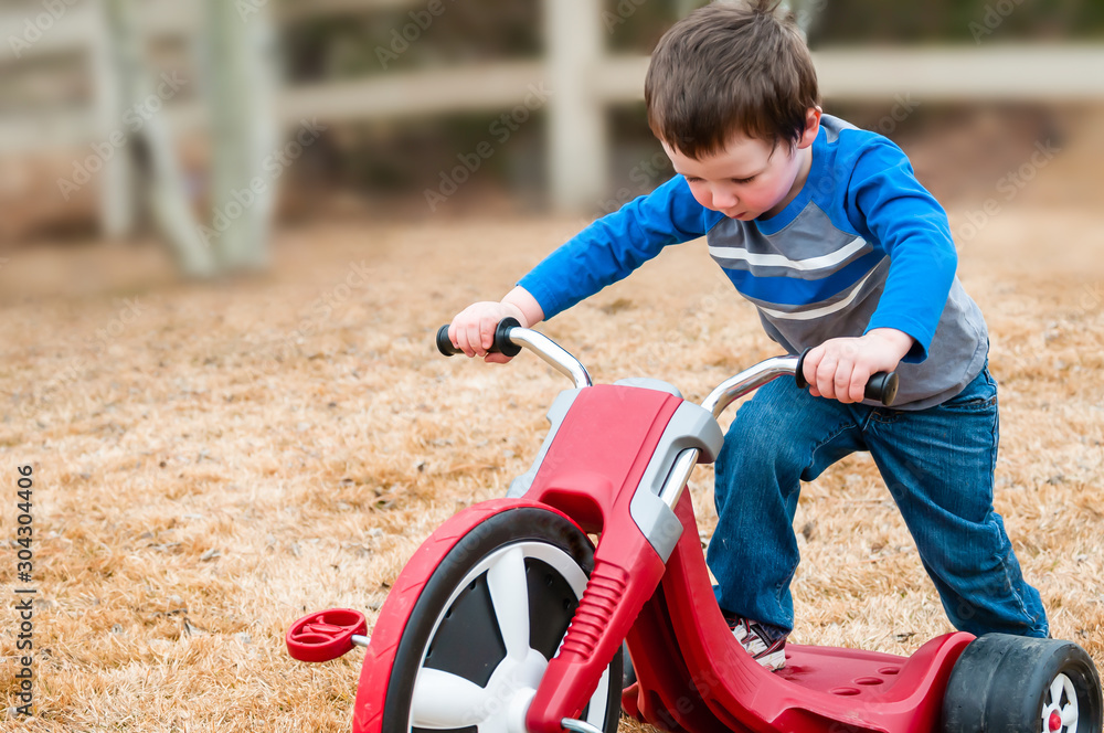 Little boy with a tricycle in the crisp autumn air Little boy with a tricycle in the crisp autumn air