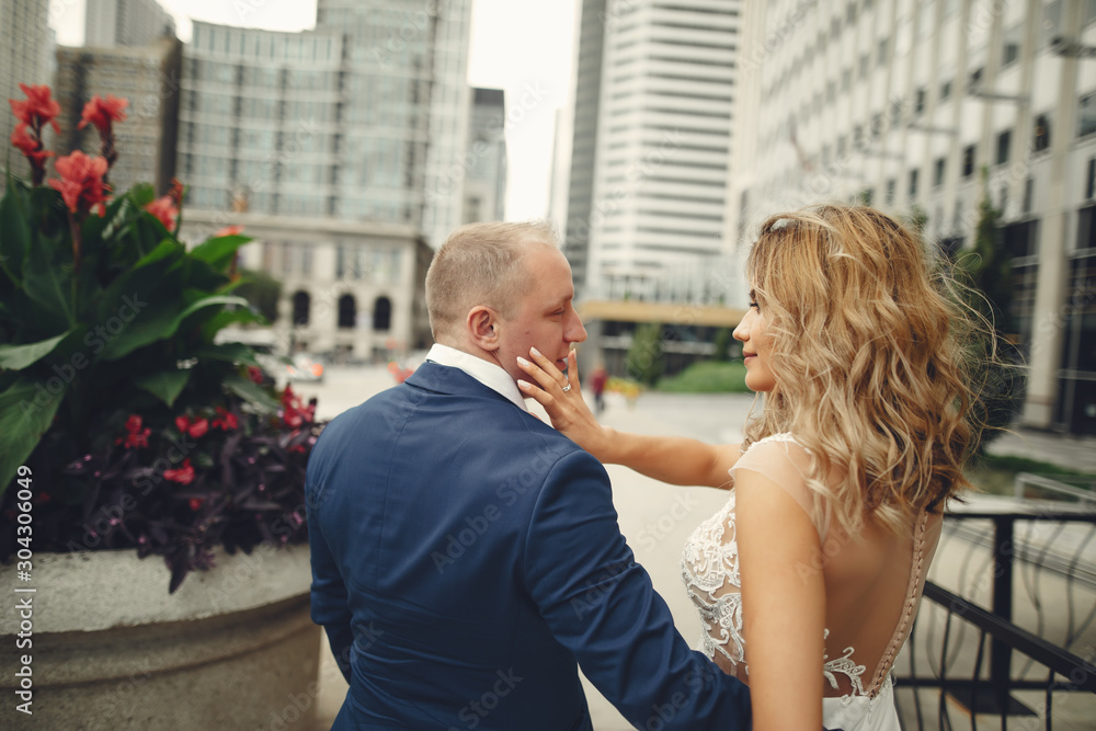 Beautiful bride in a long white dress. Handsome fiance in a blue suit. Couple in a big city Beautiful bride in a long white dress. Handsome fiance in a blue suit. Couple in a big city