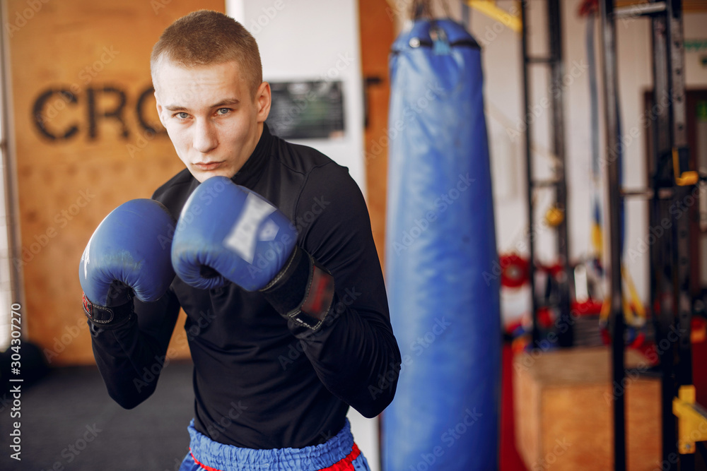 Sports man in the gym. A man performs exercises. Guy boxing
