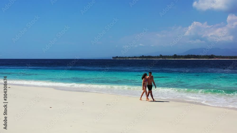 Hugging young couple walking around quiet exotic beach on a windy day with bright sky and beautiful blue turquoise sea background in Thailand Hugging young couple walking around quiet exotic beach on a windy day with bright sky and beautiful blue turquoise sea background in Thailand