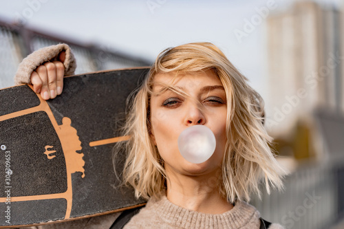 Urban stylish young girl. Outdoors emotional portrait of active woman model. Healthy lifestyle. Fashion look, outdoor hipster portrait. Close up portrait of a pretty young girl chewing bubble gum. photo