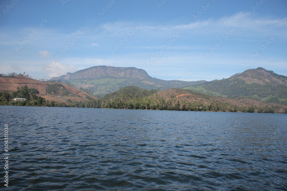 Beautiful landscape of blue-sky with a white clouds and a dry grass fields. Boating in the Ooty Lake, Reflection of blue sky and beautiful clouds in lake Ooty - Tamil Nadu
